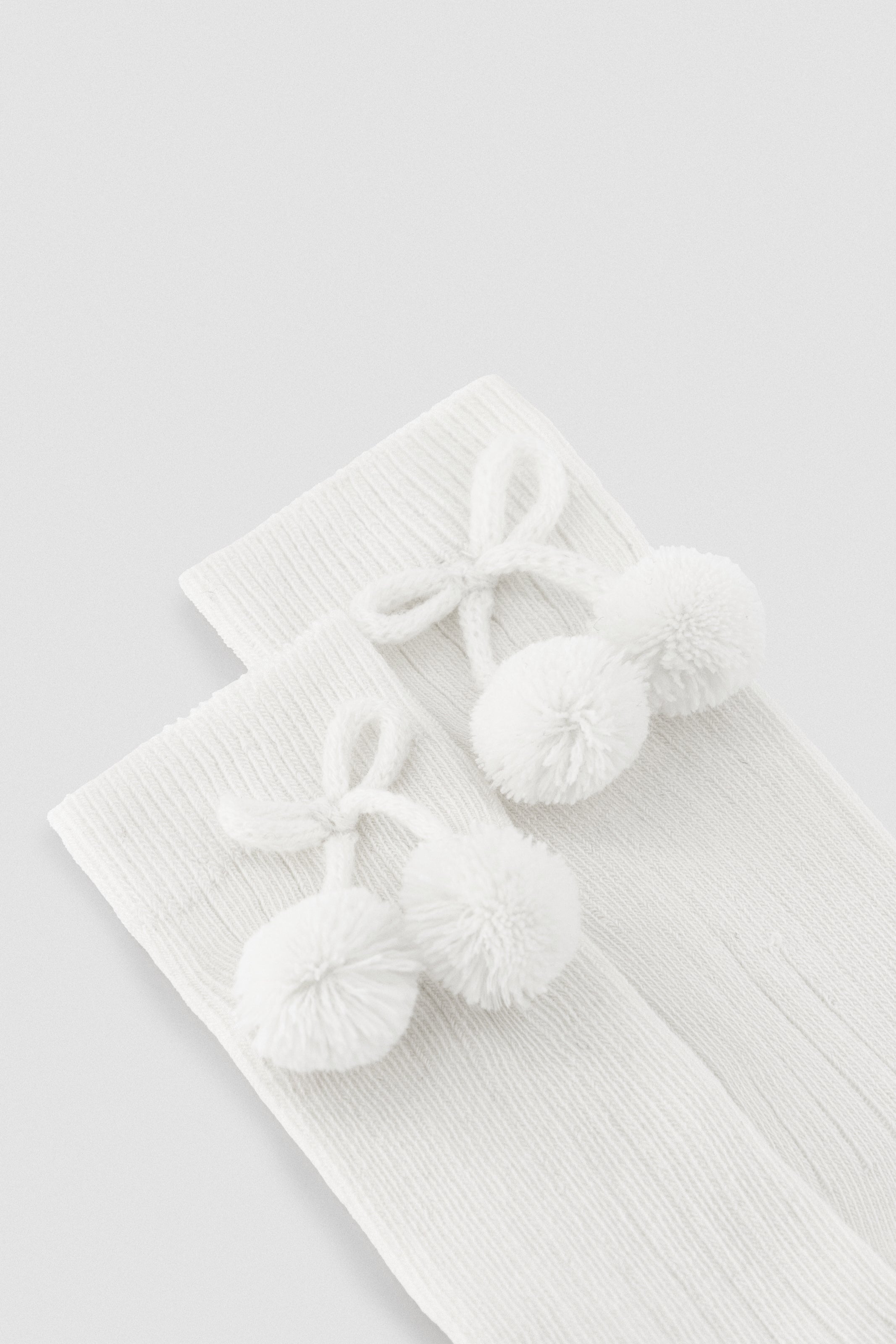 Chaussettes longues à pompons blancs